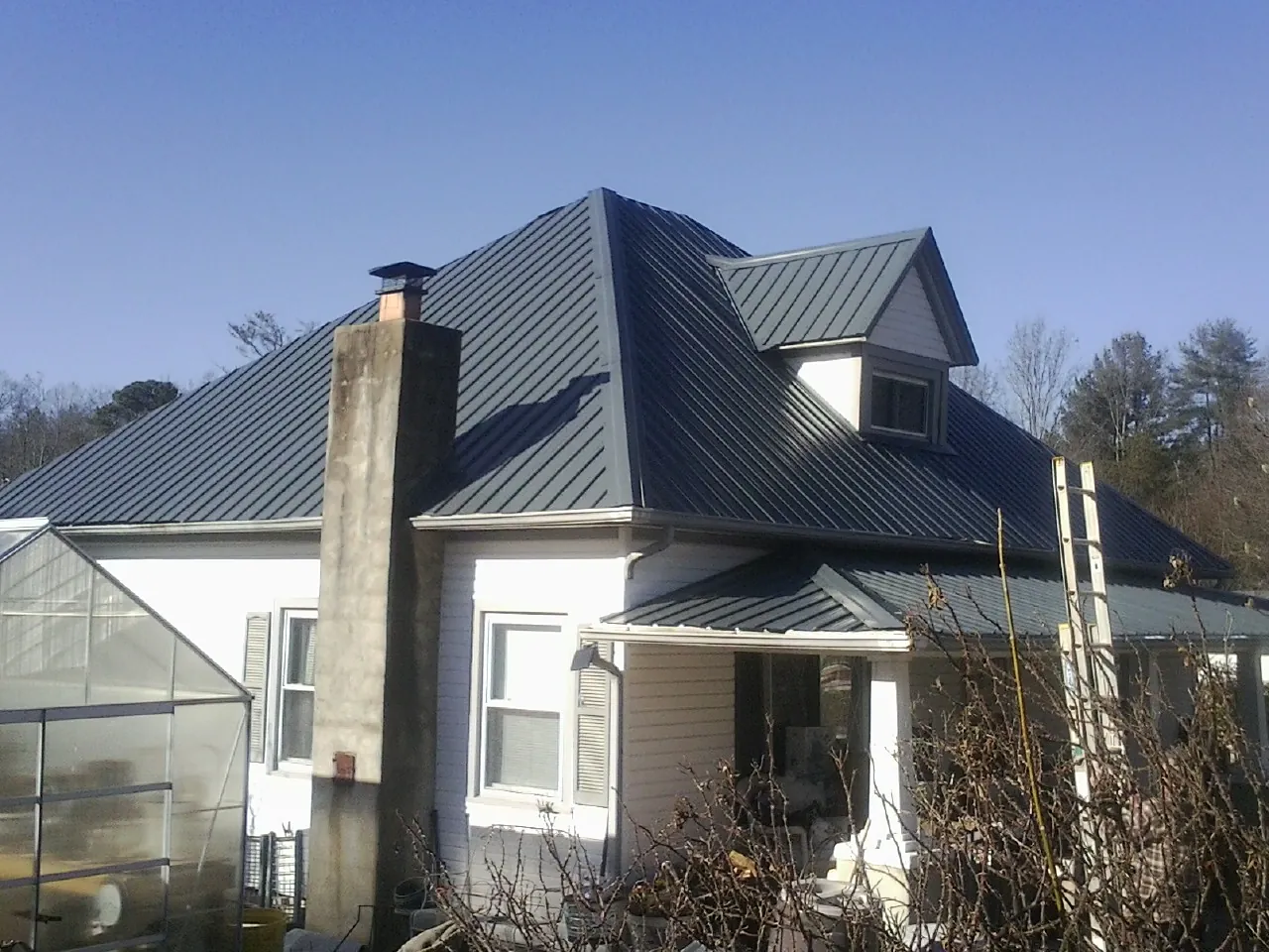 Dark blue standing seam metal roof on a white farmhouse with dormer — Slate & Tile Roof Repair by Roofing Brothers in Pearisburg