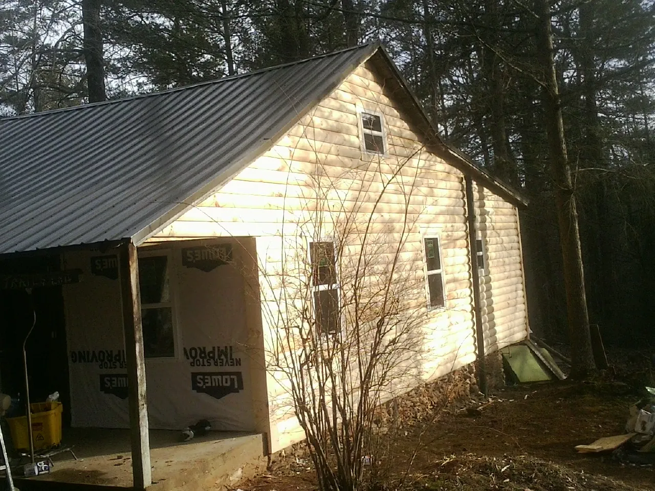 Log siding gable end under a dark metal roof edge in Pearisburg