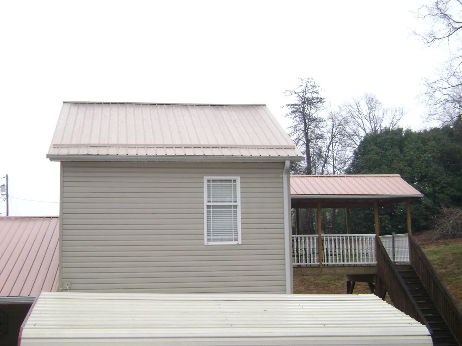 Tan metal roofs on a two story addition and attached porch, from a Roof Replacement job in Pearisburg